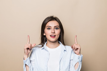 Young pretty woman pointed up isolated on beige background