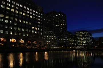 Night view of office towers reflecting in the water of the river Thames at Canary Wharf, London, United Kingdom