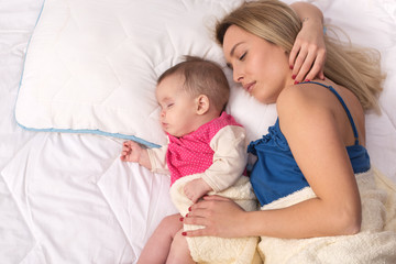 Mom and baby girl sleeping in bed