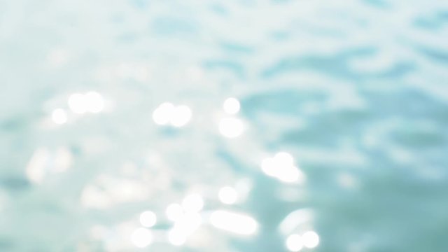 Beautiful defocused blurry abstract video background. Blurred sunny surface of blue sea water splashing at summer beach outside. Slow motion full hd footage.