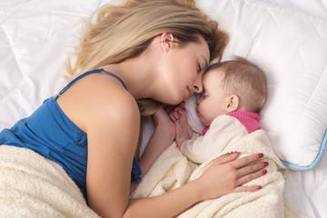 Obraz na płótnie Canvas Mom and baby girl sleeping in bed