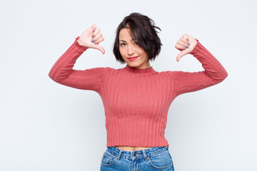 young pretty woman looking sad, disappointed or angry, showing thumbs down in disagreement, feeling...