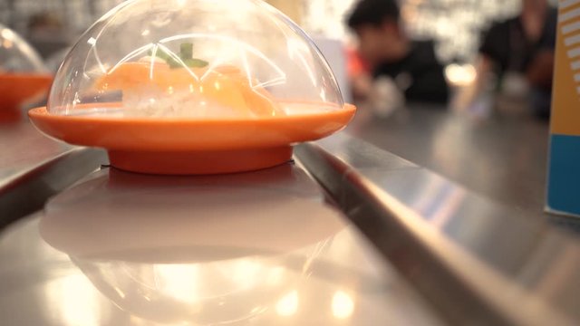 Camera on revolving sushi belt, shifting focus.