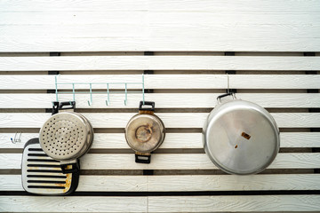 Kitchen equipments hanging at wooden white wall.