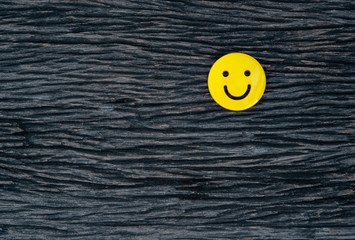 yellow emoticon smiley face icon symbol on vintage dark hard wood table background