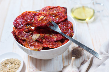 Dried tomatoes with garlic in bowl on white