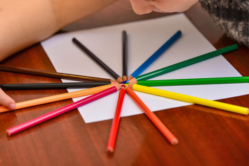 Fototapeta premium Color pencils lie on a blank white sheet on the table.