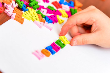 The girl adds the word "mother" from multi-colored letters.