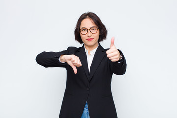 young businesswoman feeling confused, clueless and unsure, weighting the good and bad in different...