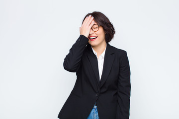young businesswoman laughing and slapping forehead like saying d‚Äôoh! I forgot or that was a...