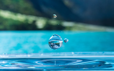 water drop splashing in a lake and reflecting the mountainsides on the background