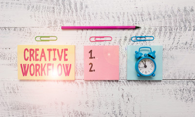 Conceptual hand writing showing Creative Workflow. Concept meaning the process undertaken by a company s is creative team Blank notepads marker small alarm clock wooden vintage background