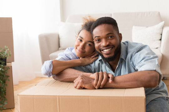 Afro Spouses Embracing Among Unpacked Moving Boxes In New Flat