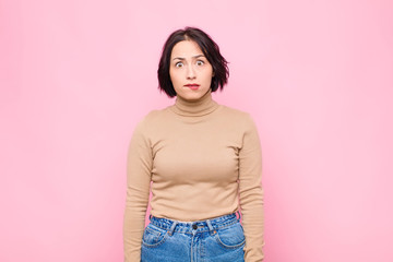 young pretty woman feeling clueless, confused and uncertain about which option to pick, trying to...