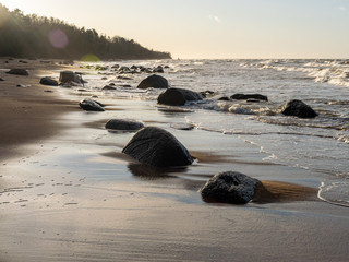 backlit landscape with stony sea shore