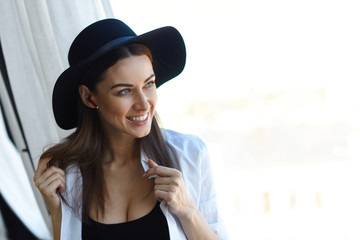 Young smile face brunette sexy naked woman in black hat with wireless earphones dressed up new...