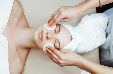 Cosmetologist remove hold sponge mask for peeling on the face of a girl in a cosmetology room