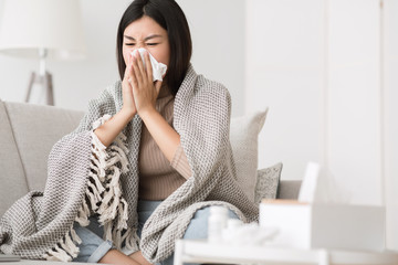 Sick at home. Girl blowing runny nose in napkin