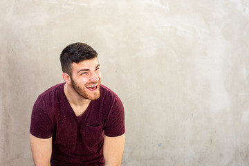 young man with beard laughing by wall