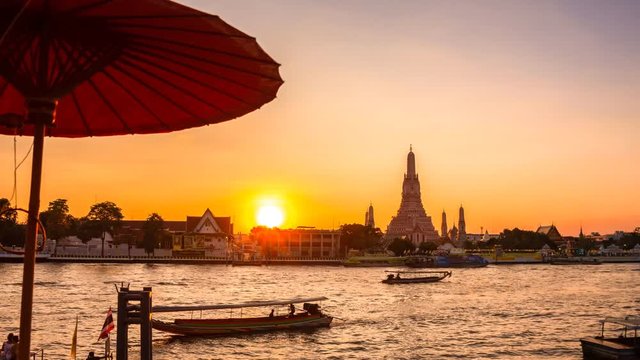 4K Timelapse view of Wat Arun of Bangkok Thailand during sunset with busy boat moving in the river