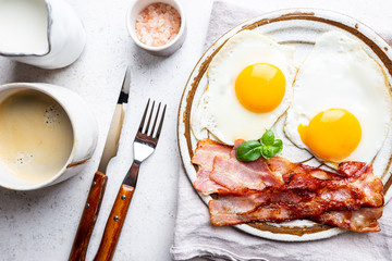 Fried eggs and bacon for breakfast on a plate, top view, copyspace