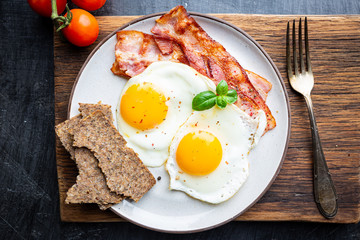 Fried eggs and bacon for breakfast on a plate, top view, copyspace