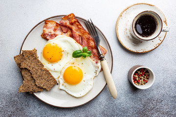 Fried eggs and bacon for breakfast on a plate, top view, copyspace