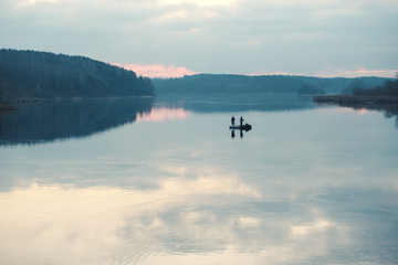 Silhouettes of fishermen in a boat on a lake surface.