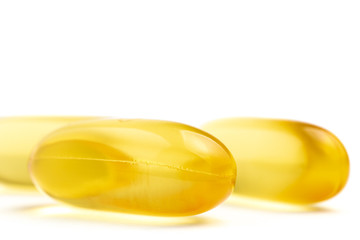 Omega 3 supplement, fish oil yellow capsules isolated on white background, macro image