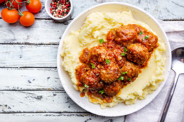 Meatballs in tomato sauce with mashed potato on the white plate, top view, view from above