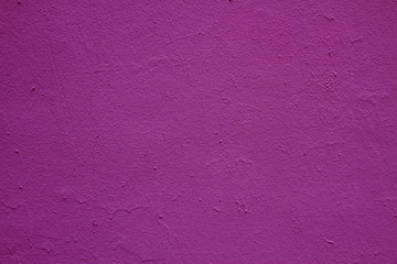 Old peeling paint on the wall.  Beautiful purple textured stucco on the wall. Background from purple stucco.