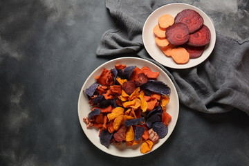 Baked vegetable chips- garnet sweet potato, purple sweet potato,carrot and beetroot. Gluten-free, dairy-free and vegan. Healthy food concept