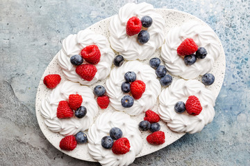 White meringues cakes with berries, raspberry and blueberry. Flat lay, top view
