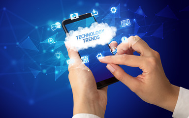Female hand holding smartphone with TECHNOLOGY TRENDS inscription, cloud technology concept