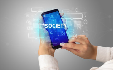 Female hand typing on smartphone with SOCIETY inscription, social media concept