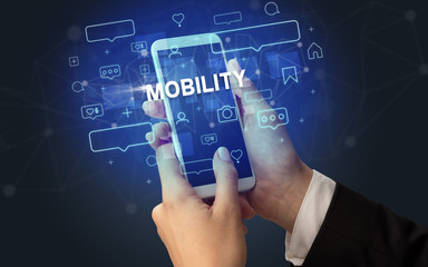 Female hand typing on smartphone with MOBILITY inscription, social media concept