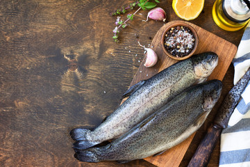 Fresh raw trout fish and pickle ingredients on a wooden table. Cooking grilled fish preparation. Top view flat lay background. Copy space.