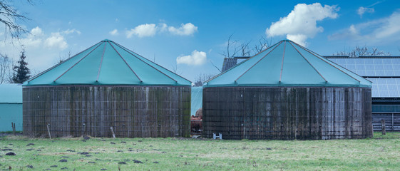 Zwei alte Biogasanlagen Türme aus Holz mit einem grünen Planen Dach