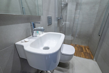Stylish modern white vessel sink under mirror and water faucet in home bathroom interior. Shower room at apartment