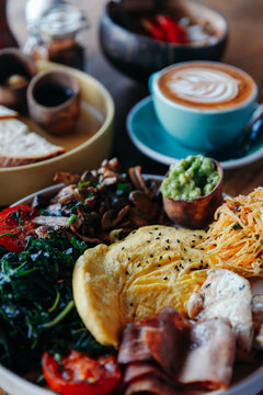 Morning breakfast on a table, waffles with cream, berries, coffee, cappuccino, bowl, omlet with vegetables, bread with butter, avocado cream, vegan food, healthy food, meal.