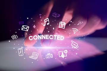 Finger touching tablet with drawn social media icons and CONNECTED inscription, social networking concept