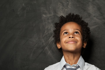 Little child boy looking up on blackboard background