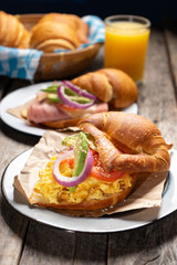 Butter croissant bread with scrambled eggs and avocado on wooden background