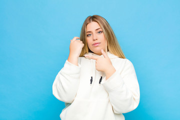young blonde woman looking impatient and angry, pointing at watch, asking for punctuality, wants to...