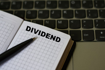 notebook with the word dividends on the background of a laptop
