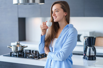 Happy attractive smiling female drinking and enjoying hot fresh aromatic coffee after brewing...