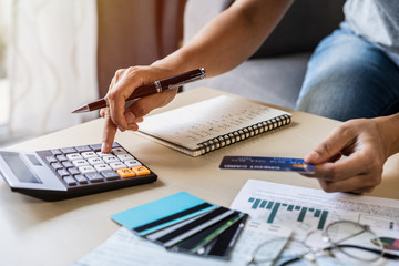 Young woman checking bills, taxes, bank account balance and calculating credit card expenses at home