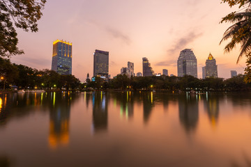 Fototapeta na wymiar Landscape of the tall building with water reflaction at Lumpini park , Bangkok , Thailand. The Building in capital of Thailand with sunset at Lumpini park.