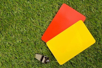 Soccer sports referee yellow and red cards with chrome whistle on grass background flat lay from...