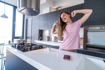 Sleepy woman with closed eyes in pajamas stretching after waking up early in the morning before preparing breakfast in the kitchen at home. Beginning and start new happy day